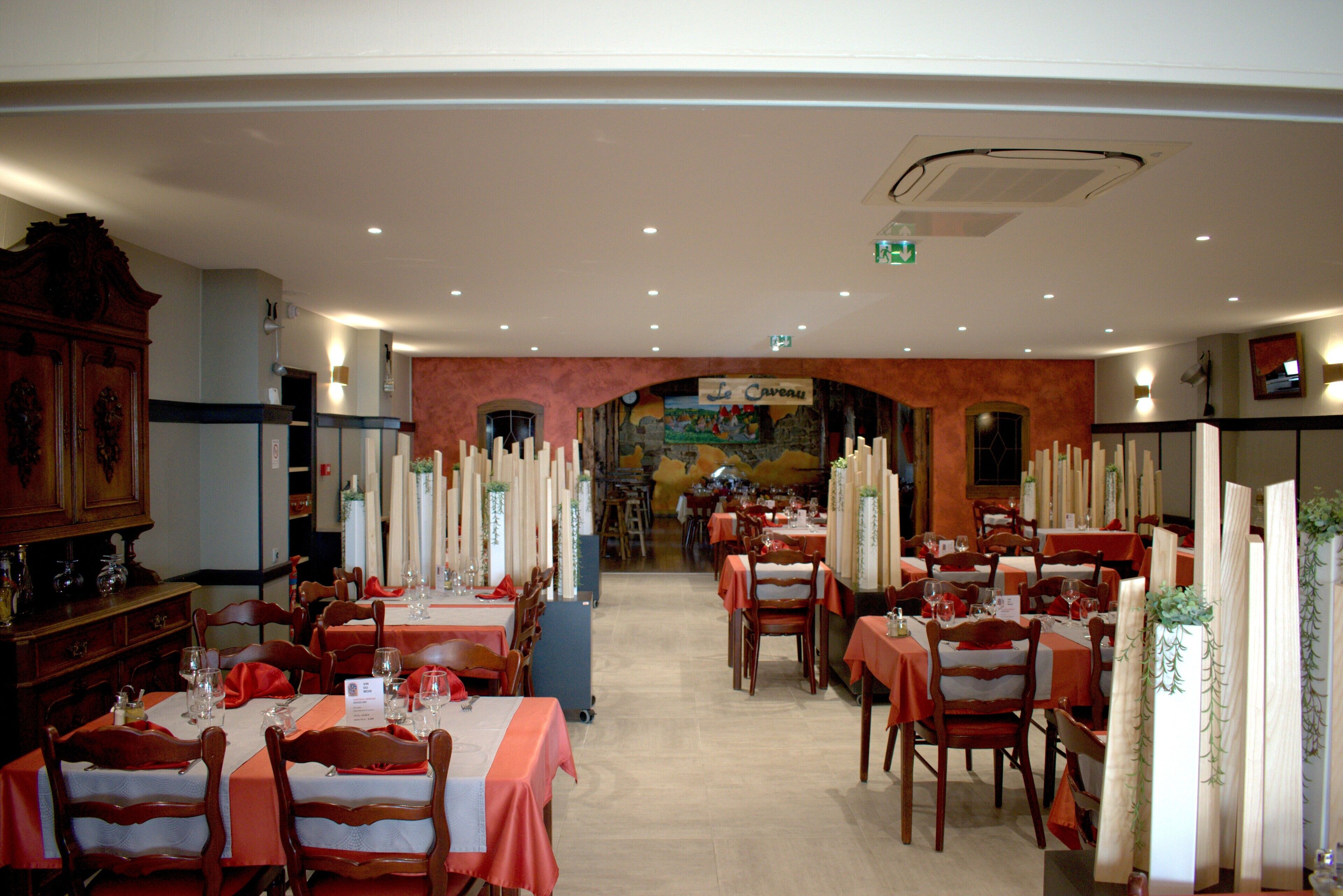 Un restaurante con varias mesas y sillas, un mural grande en la pared, y un letrero que dice 'Le Couver'.