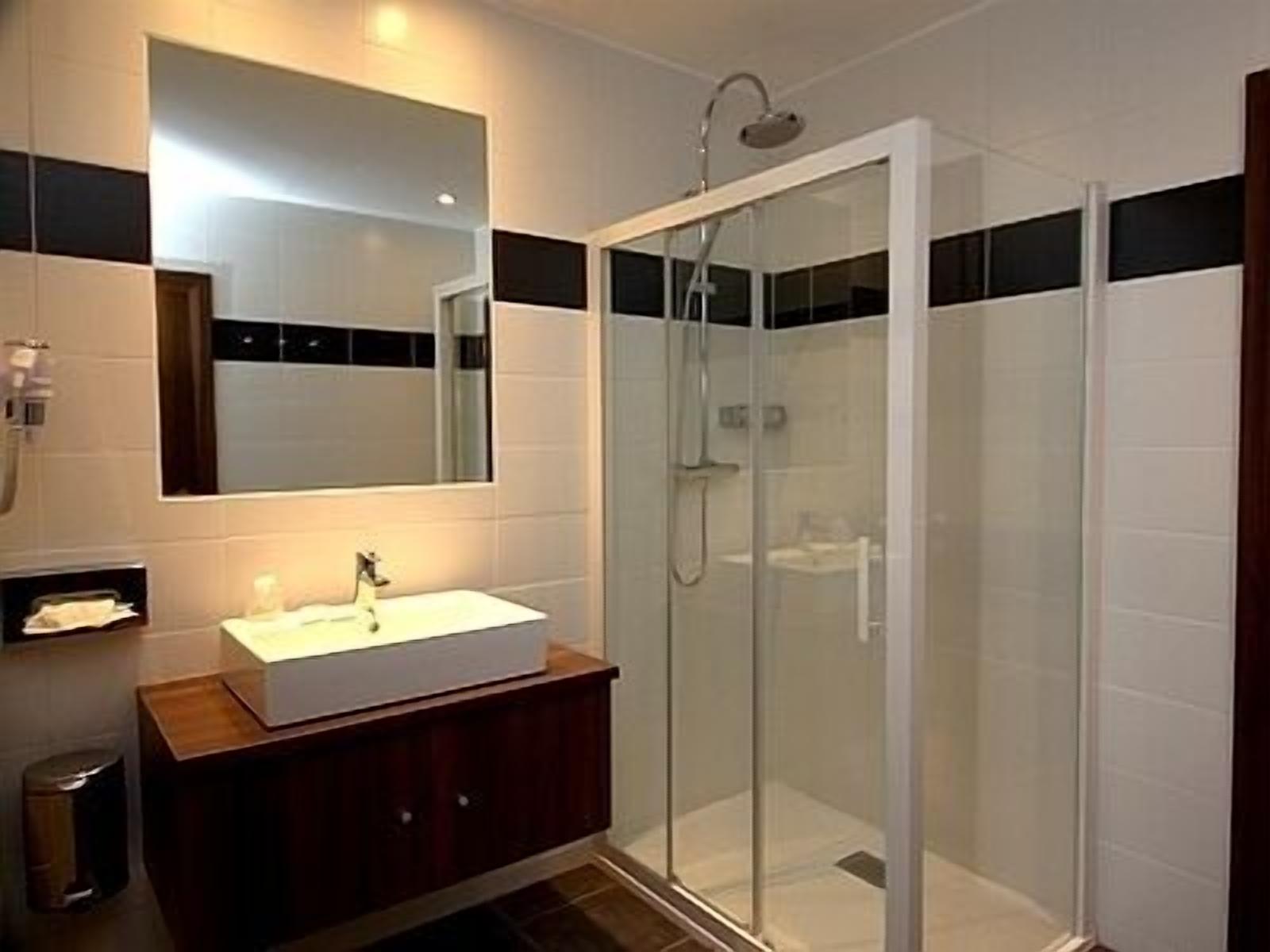 A modern bathroom with a glass-enclosed shower, a white sink, and a wooden vanity.