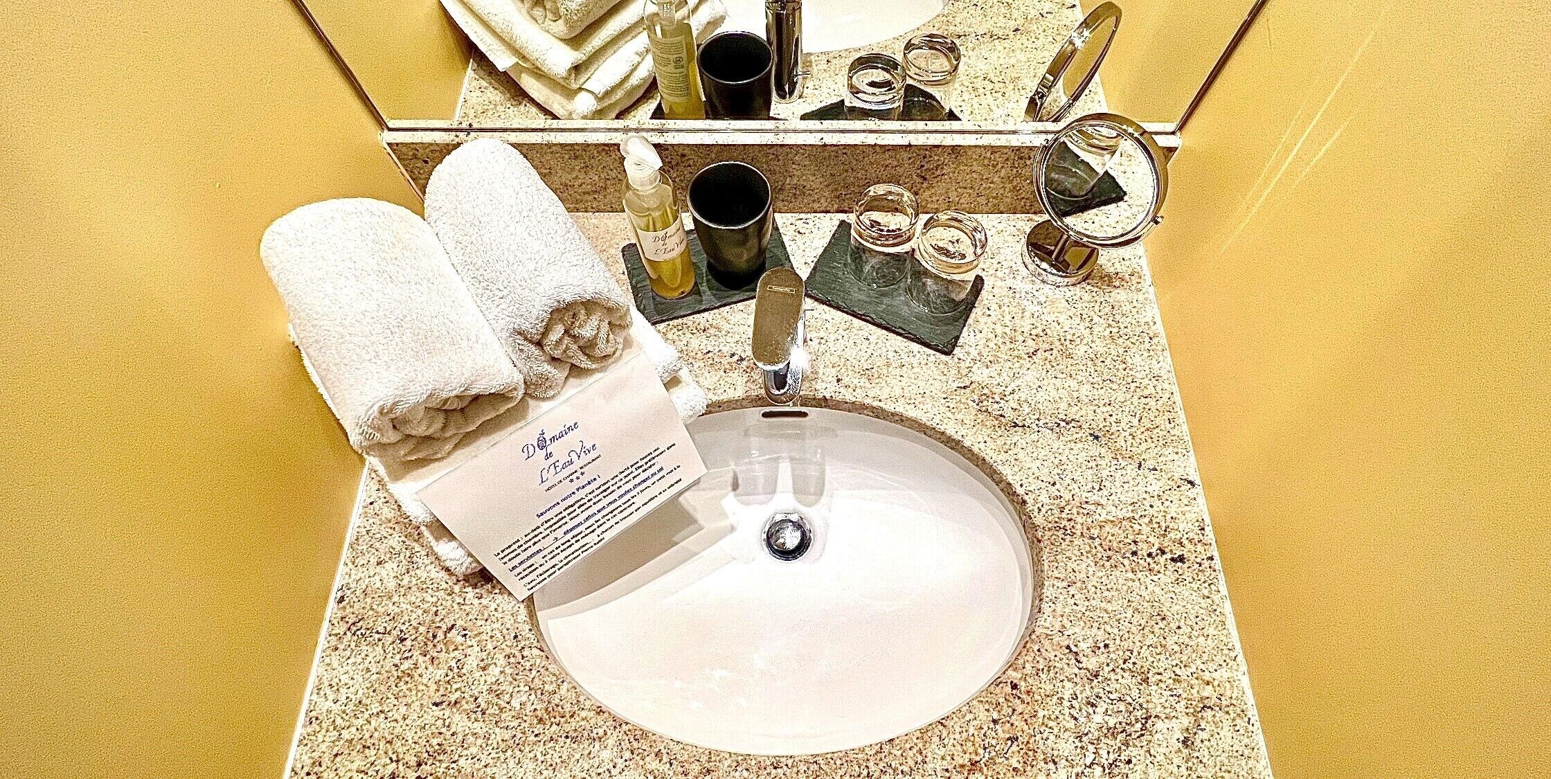 A bathroom with a sink, a mirror, and toiletries on the counter.