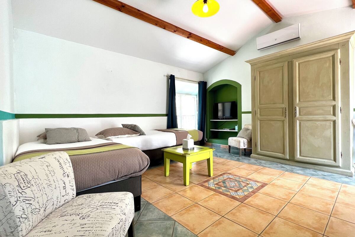 A hotel room with a bed, a sofa, a small table, a television, and a wardrobe.