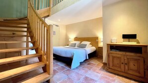 A bedroom with a wooden staircase, a bed with pillows, a nightstand, and a cabinet.