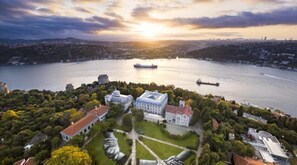 An aerial view of a cityscape with a large body of water, a prominent building complex with classical architecture, and a ship in the distance. - Nowy Efendi Hotel - Special Class (Istanbul)