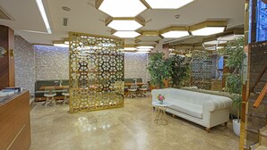 Un vestíbulo con mostrador de recepción, zona de estar y escalera.