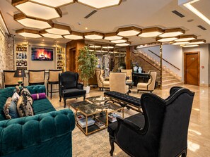 Un vestíbulo de hotel con chimenea, zona de estar y una escalera.