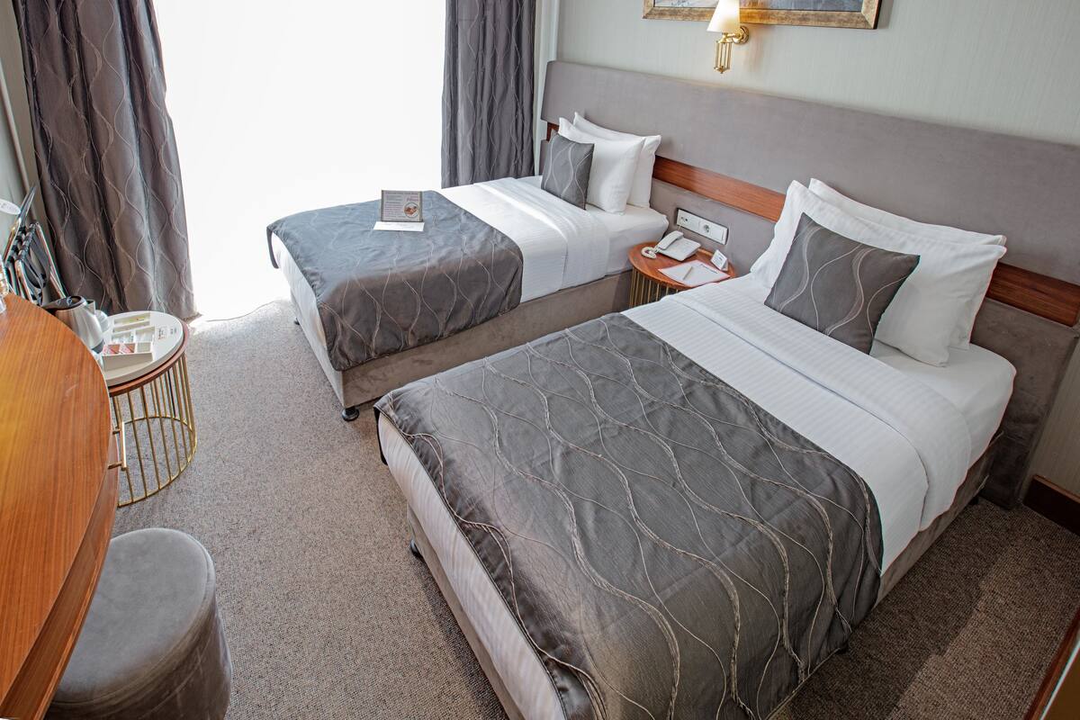 Ein Hotelzimmer mit zwei Betten, einem Schreibtisch und einem Stuhl.