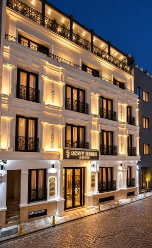 Un hotel de varios pisos con un estilo arquitectónico clásico, con balcones y barandillas ornamentadas, y un letrero de hotel visible.
