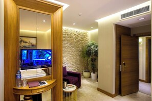 A modern hotel room with a stone wall, a television, a small table with a tray, and a purple armchair. - Nowy Efendi Hotel - Special Class (Istanbul)