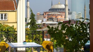Vista de una mezquita con dos minaretes y una cúpula grande, visible a través de una ventana con balcón.