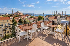 Un balcón con mesa y sillas que da a vistas de un paisaje urbano con edificios históricos.