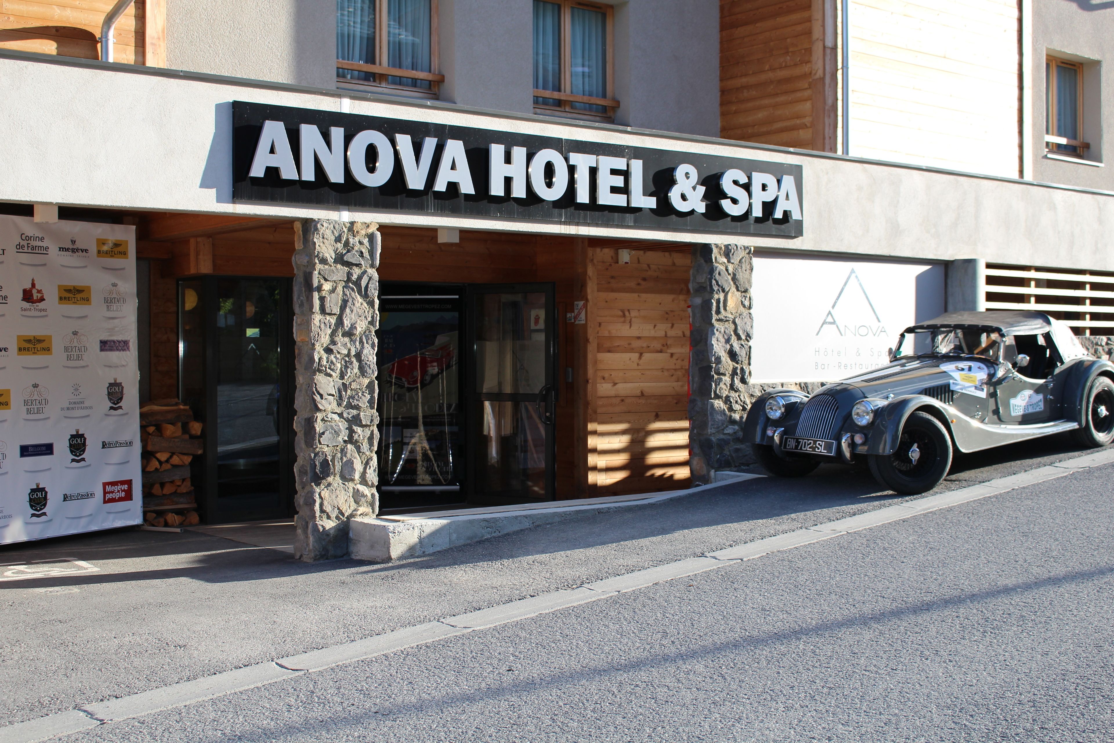 The exterior of Anova Hotel & Spa with a vintage car parked in front.