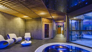 Uma área de spa moderna com hidromassagem, espreguiçadeiras e uma parede de pedra.
