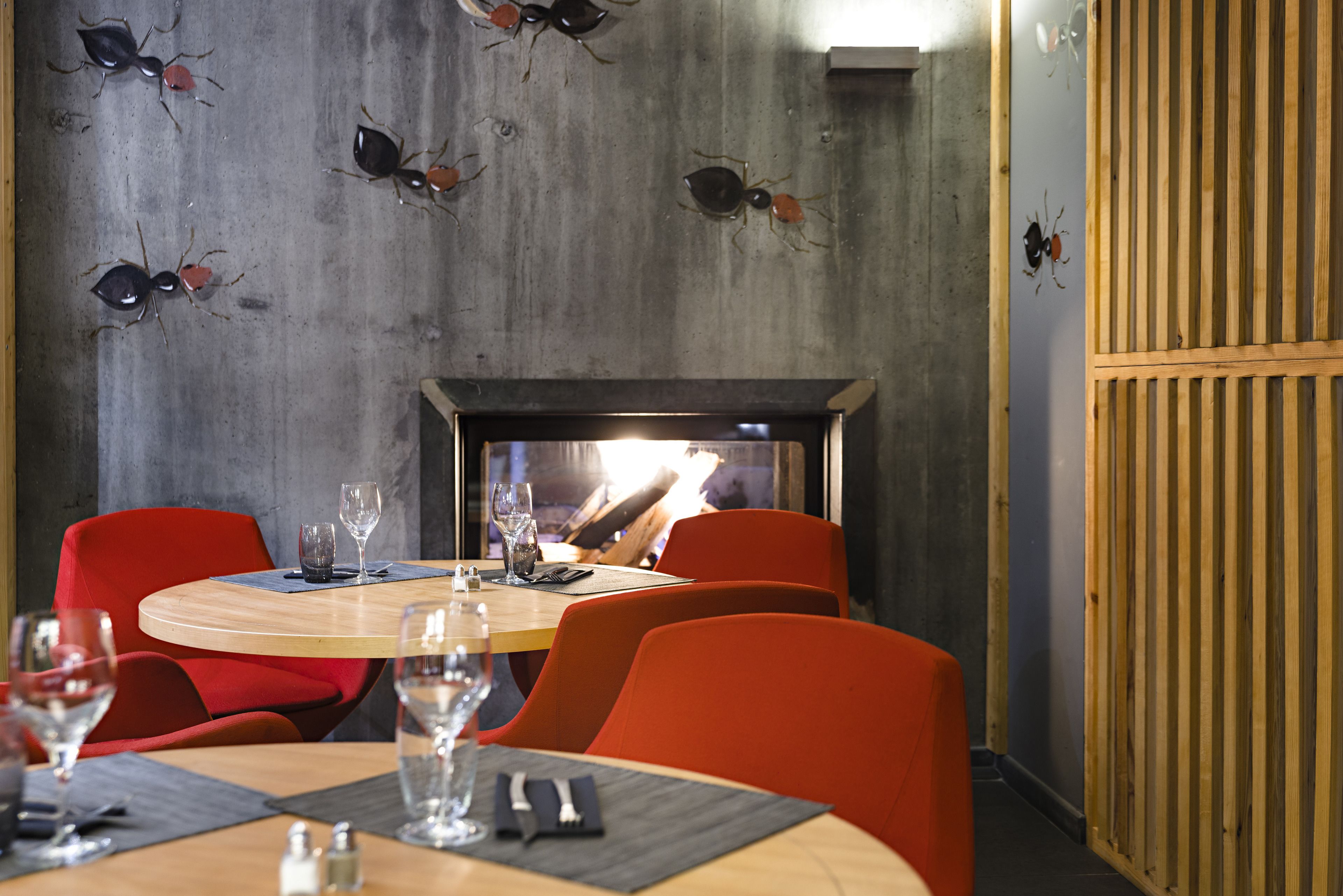A restaurant with round tables, red chairs, and a fireplace.