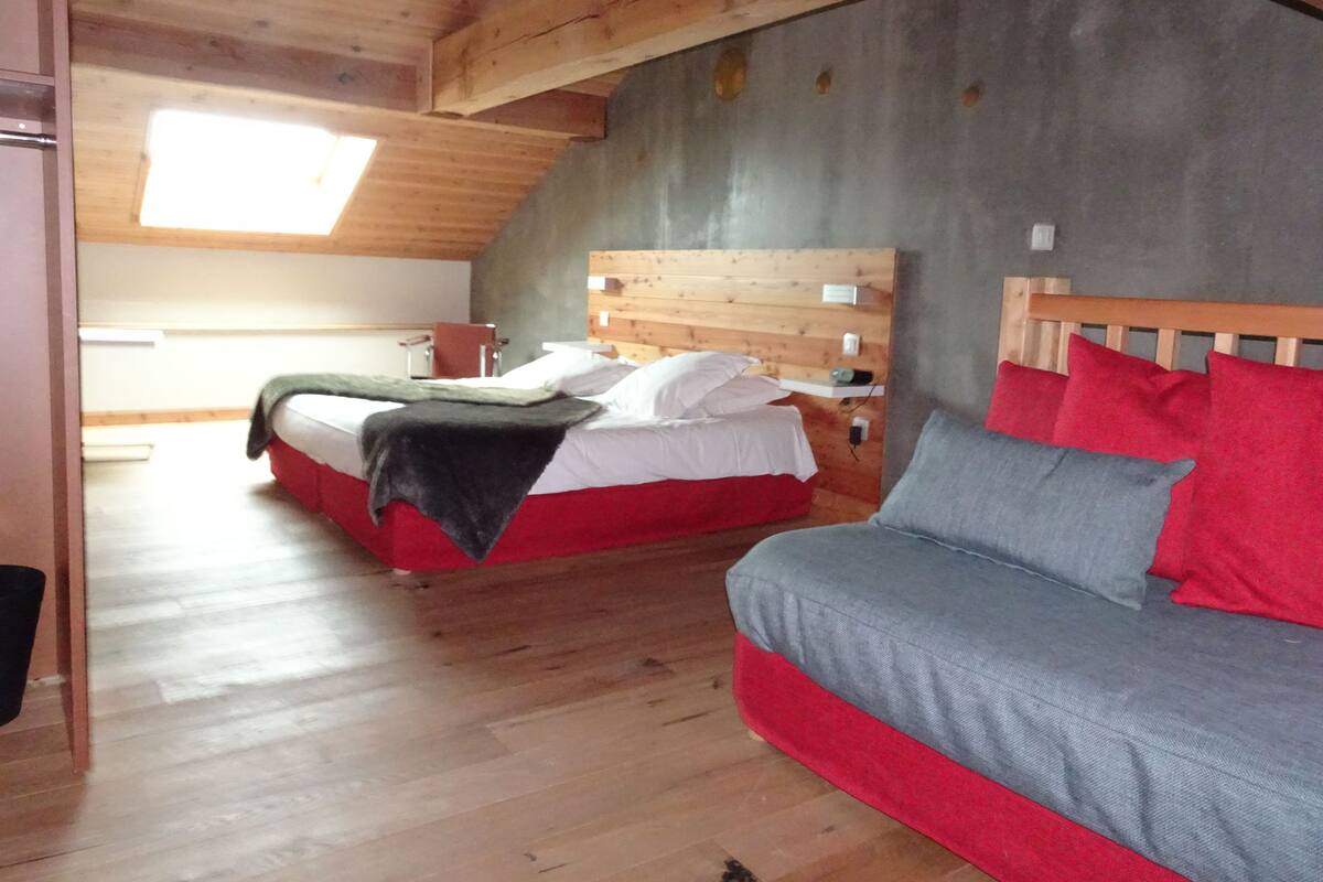 A bedroom with two beds, a wooden ceiling, and a concrete wall.