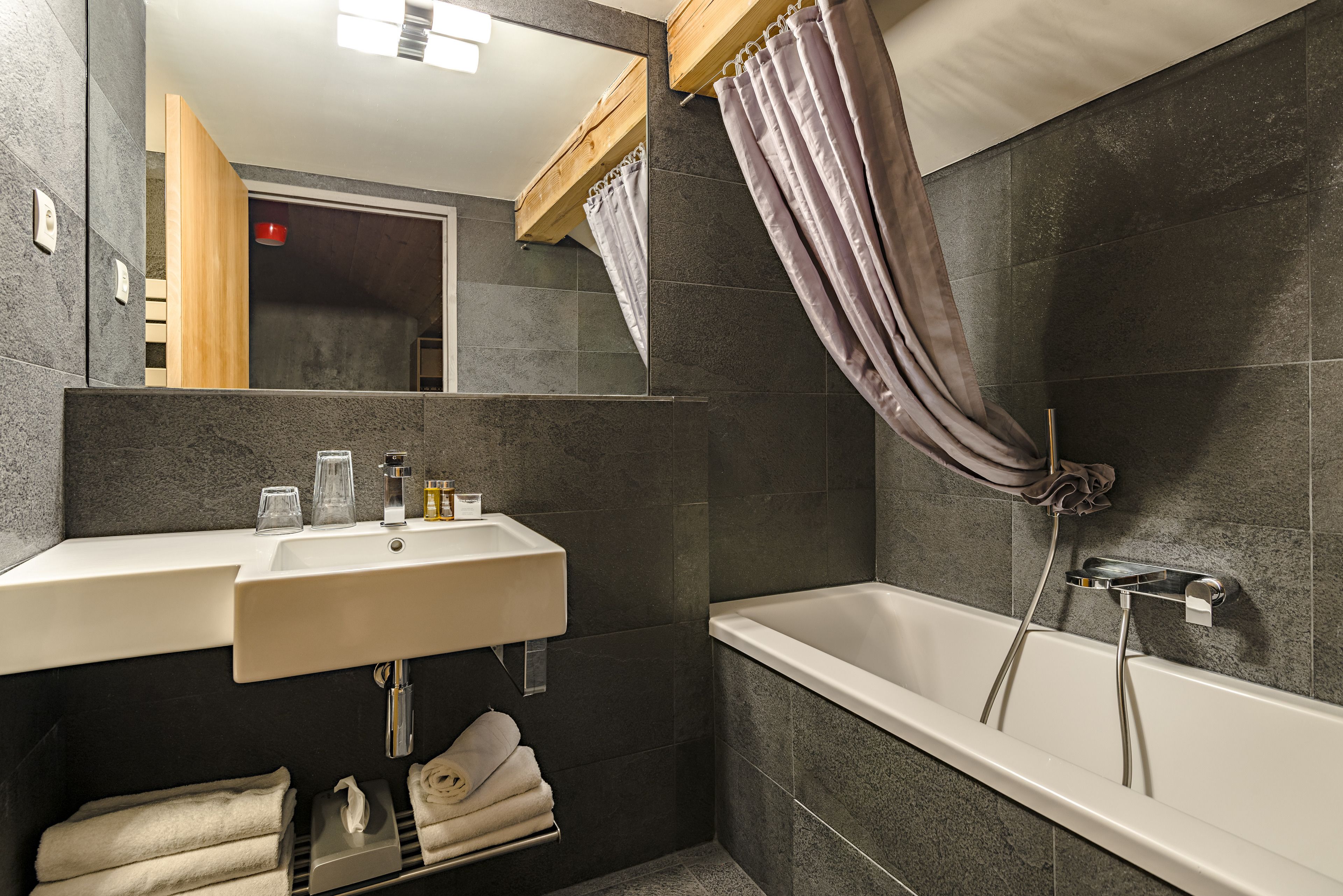 A modern bathroom with a white sink, mirror, and bathtub.