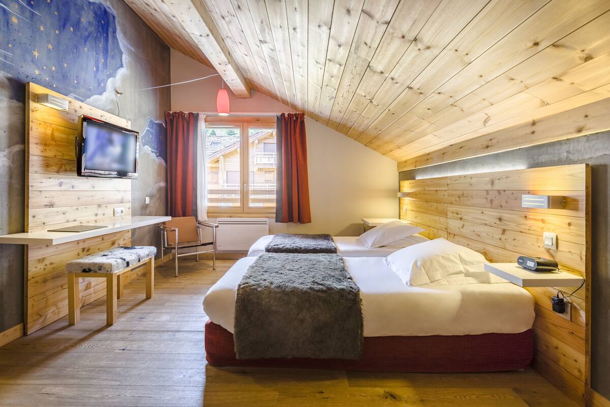A cozy room with a bed, a desk, and a TV.