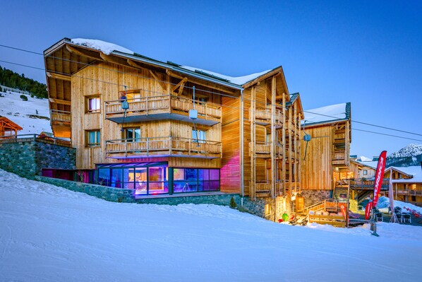 A multi-story wooden building with balconies and a ski lift in the background. - Anova Hotel & Spa (Montgenevre)