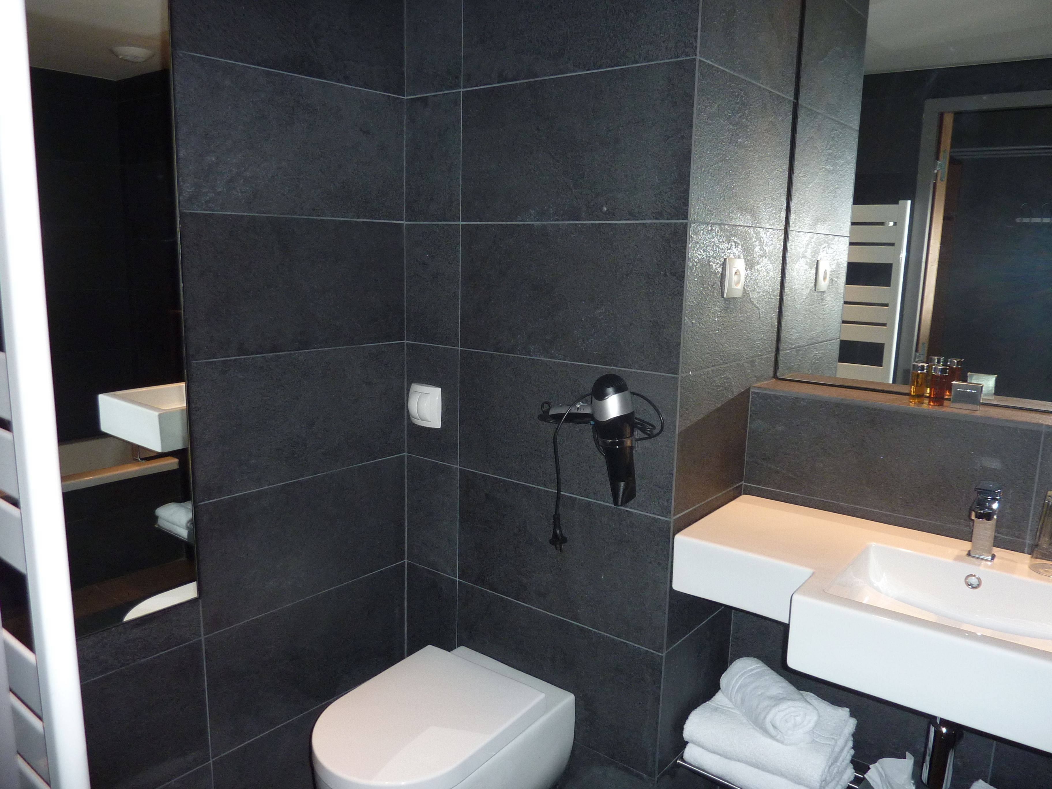 A modern bathroom with a white toilet, a sink, and a mirror.