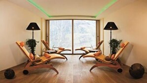 Una habitación con dos sillones de madera orientados a un ventanal amplio, una lámpara de pie y una planta en maceta.