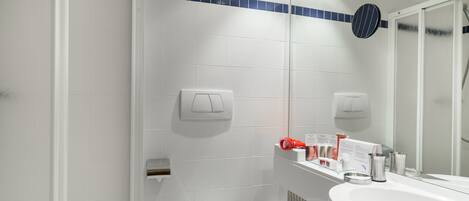A bathroom with a white toilet, a sink, and a shower area.