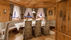 Comedor de madera con techo alto, sillas estampadas y una mesa dispuesta para cuatro.