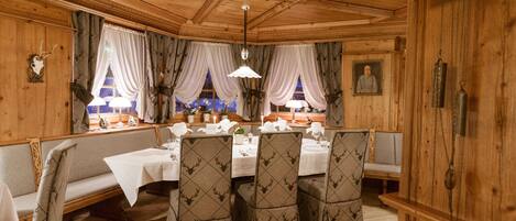 A wooden dining room with a high ceiling, patterned chairs, and a table set for four.