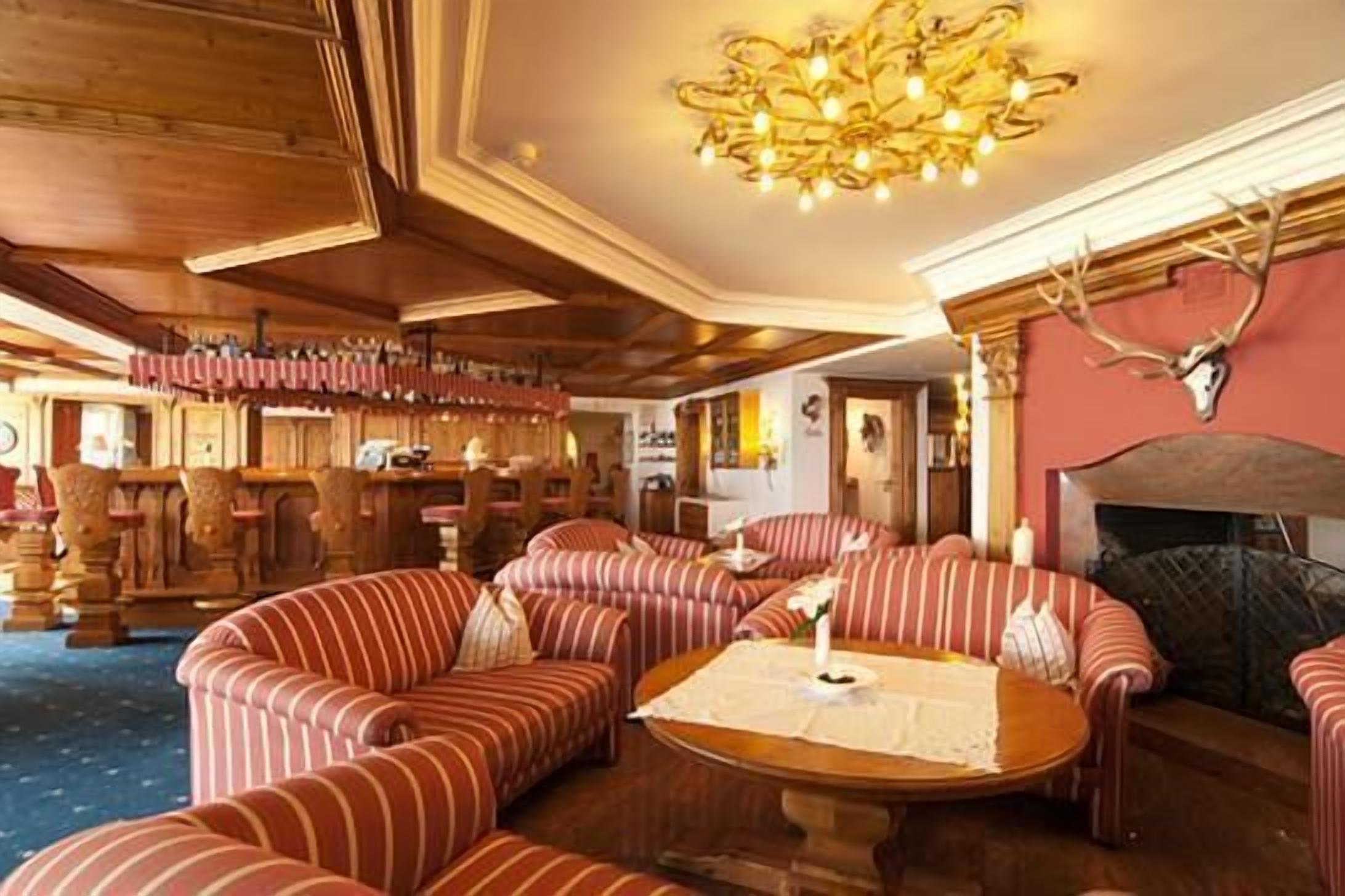 Un rincón tranquilo con sofás a rayas, una mesa redonda de madera y un candelabro.