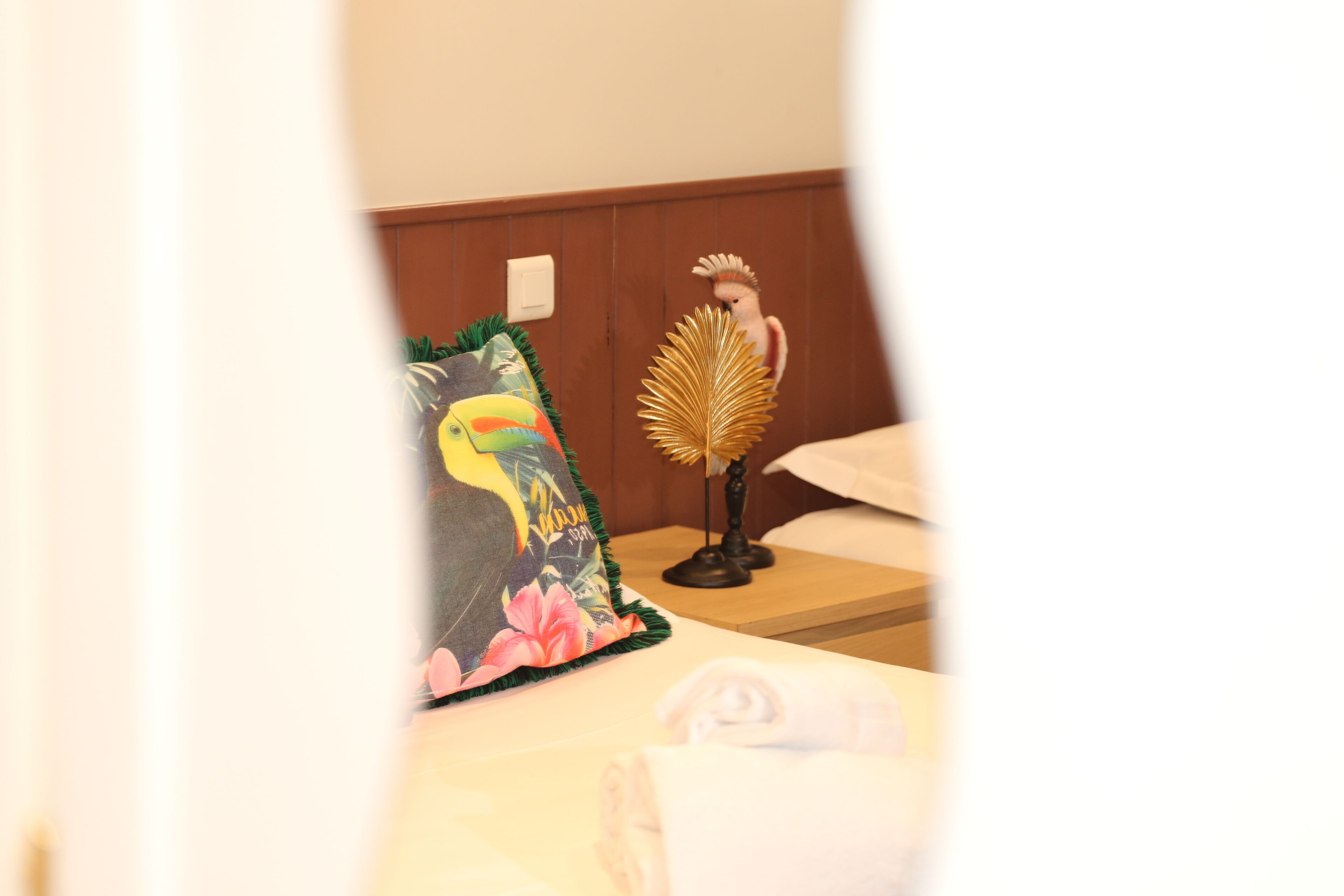 Een hotelkamer met een bed, een decoratief kussen, een klein beeldje en een nachtkastje.