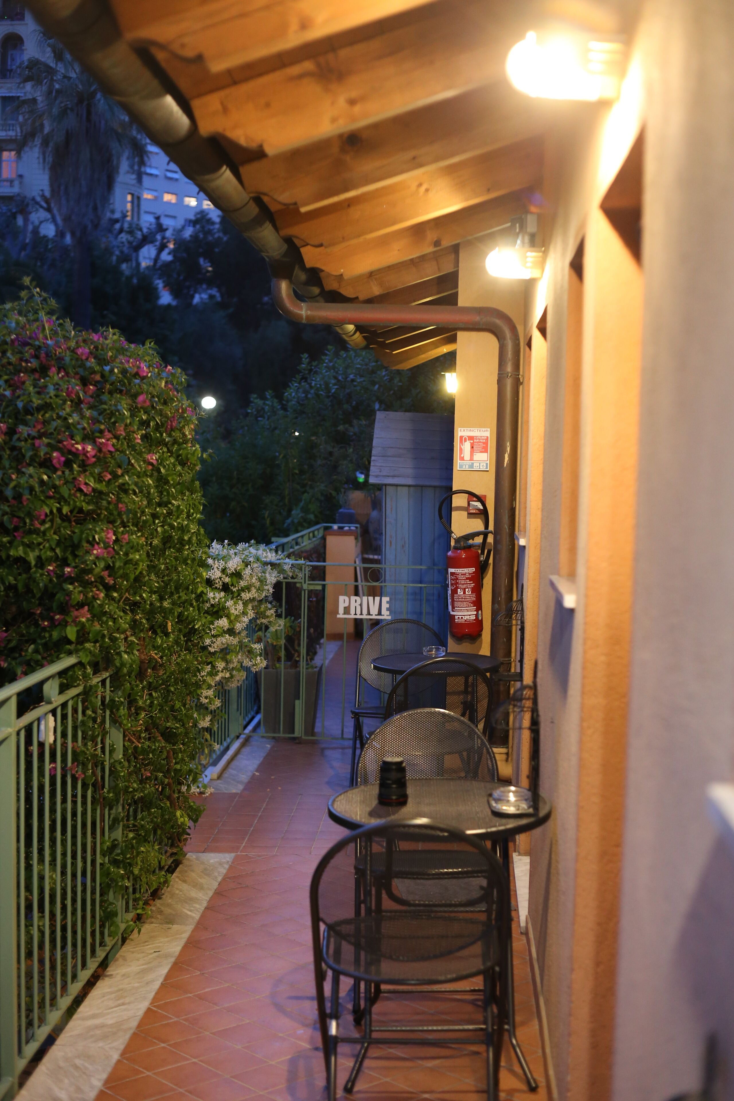 An outdoor patio with a table and chairs, a fire extinguisher, and a sign that reads "PRIVE."