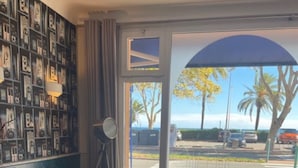 Una habitación con un ventanal grande, una estantería, una mesa redonda y dos sofás.