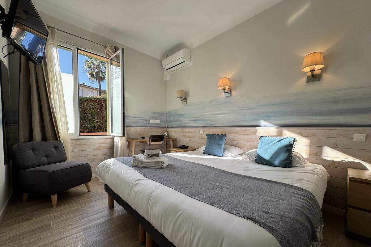 A modern hotel room with a large bed, a desk, a chair, and a TV.