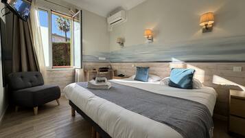 A modern hotel room with a large bed, a desk, a chair, and a TV.