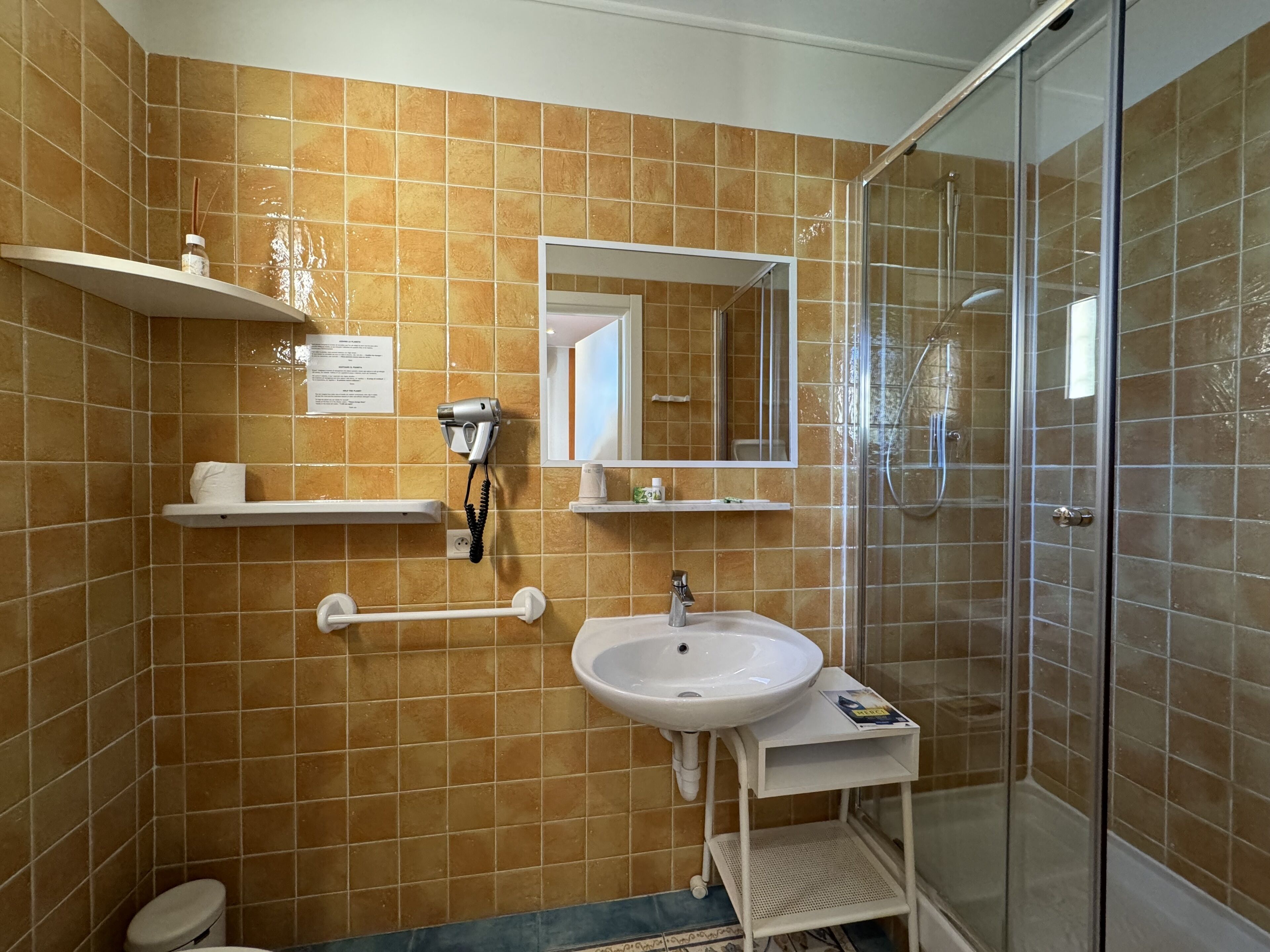 A bathroom with a sink, mirror, towel rack, and a glass-enclosed shower.