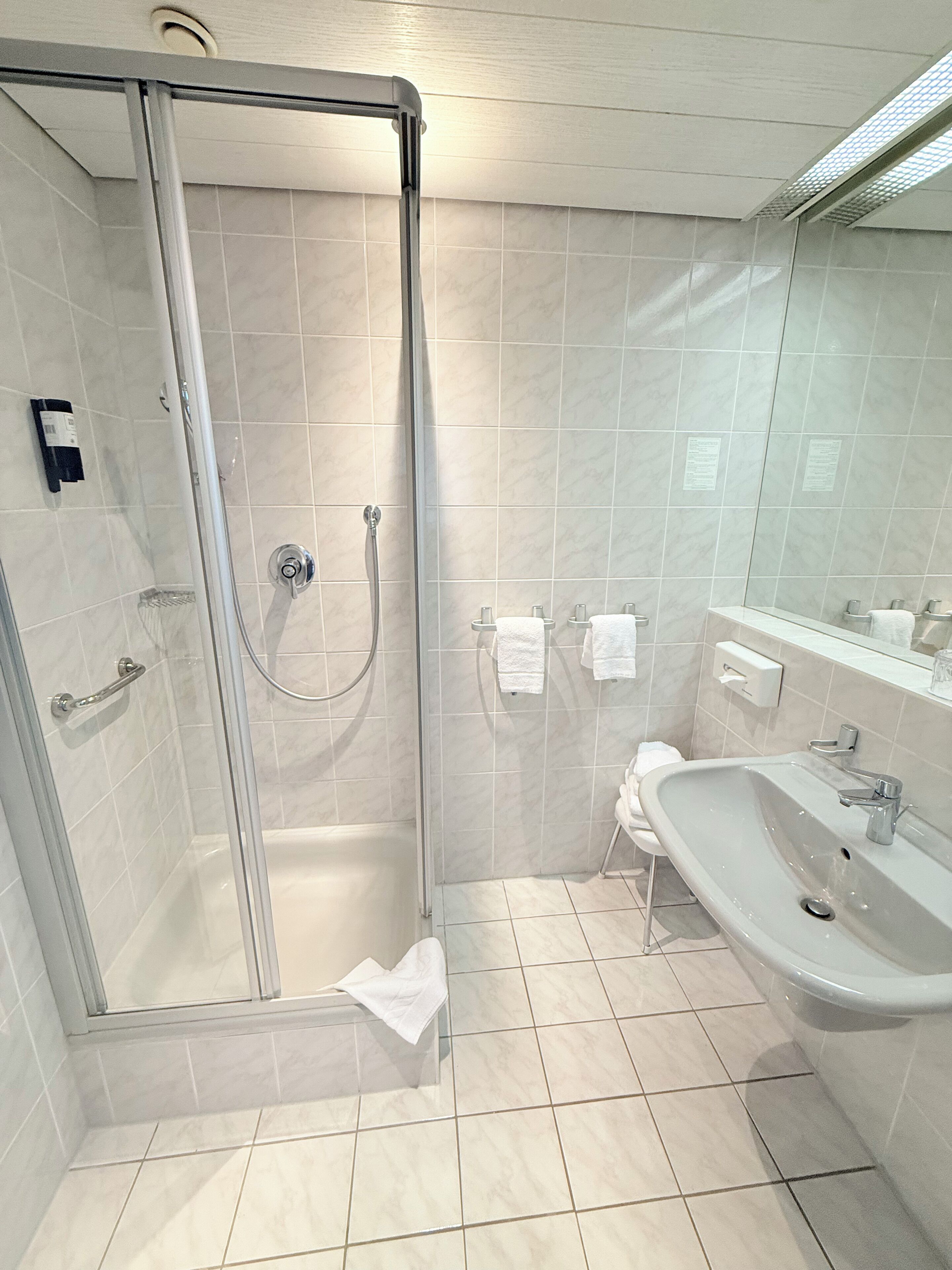 Une salle de bain moderne avec une douche à parois de verre, un lavabo et un miroir.