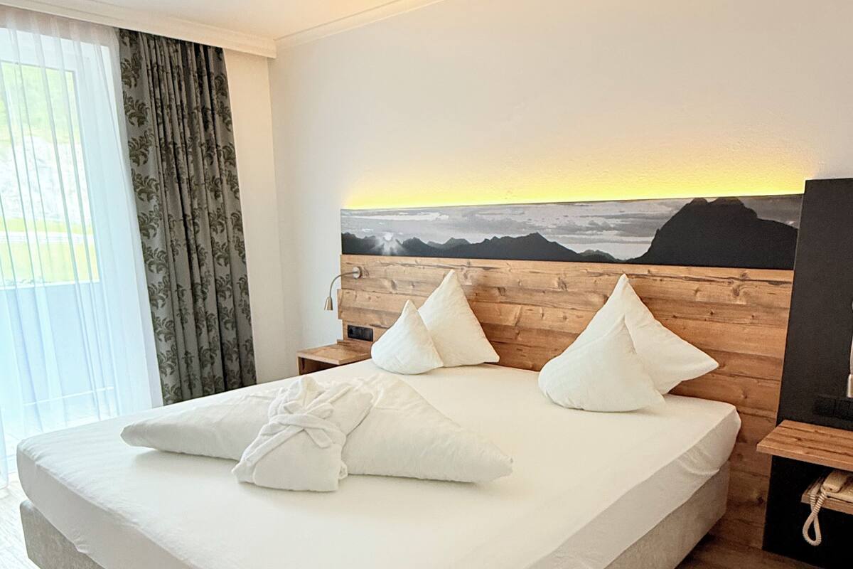 A large bed with a wooden headboard, white bedding, and multiple pillows.