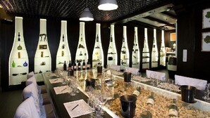 Zona bar con un lungo bancone, bicchieri da vino, bottiglie e un design originale per la cantina.