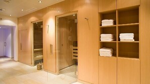 Una camera d'albergo con un armadio in legno, un guardaroba con ante in vetro e asciugamani ordinatamente piegati sugli scaffali.