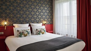 A hotel room with a large bed, red headboard, and a patterned wallpaper. - Hôtel Marsiho by Happyculture (Marseille)