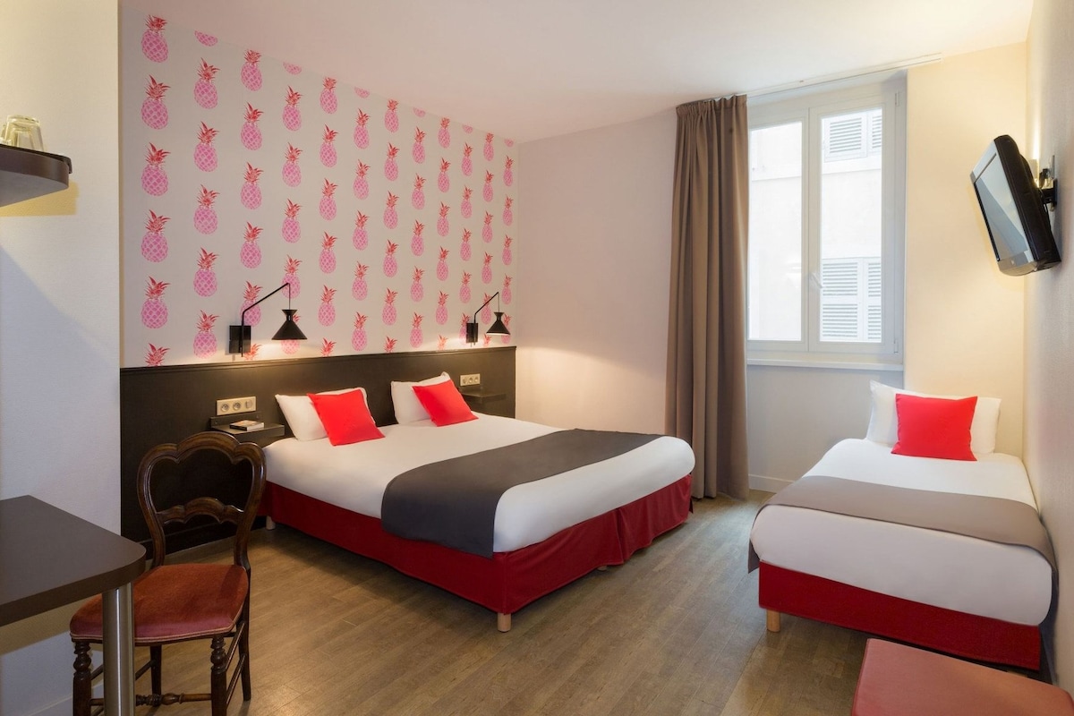 A hotel room with two beds, a desk, and a chair.