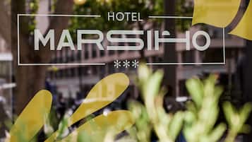 Visão desfocada de uma janela de hotel com o nome "MARSIIHO" visível.