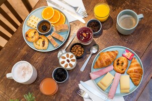 A breakfast table with plates of food, drinks, and condiments.