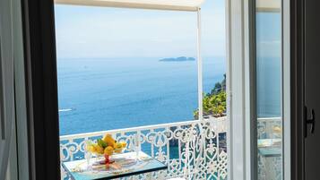 A balcony with a table set with lemons and glasses, overlooking the sea.