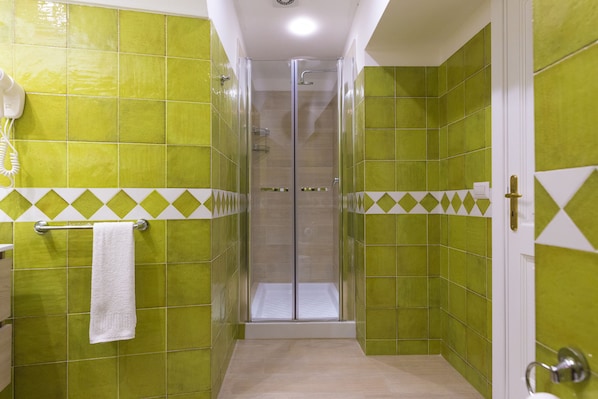 A bathroom with green tiles, a glass-enclosed shower, and a white towel hanging on a rack. - B&B Casa Nilde Positano (Positano)