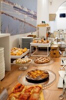 Un buffet ricco di pasticcini e dolci, un grande quadro appeso al muro e stoviglie disposte con cura.