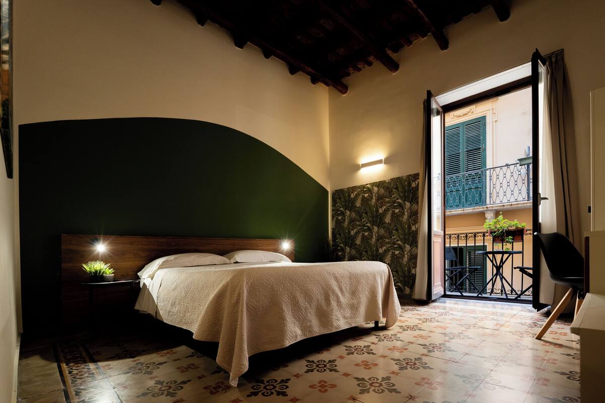 A bedroom with a bed, nightstand, and a view of a balcony.
