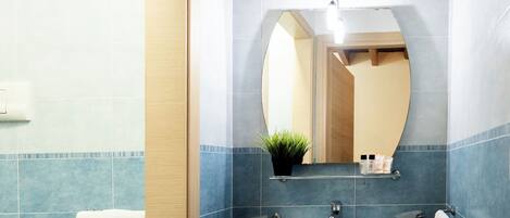 A bathroom with a pedestal sink, a mirror, and a bidet.
