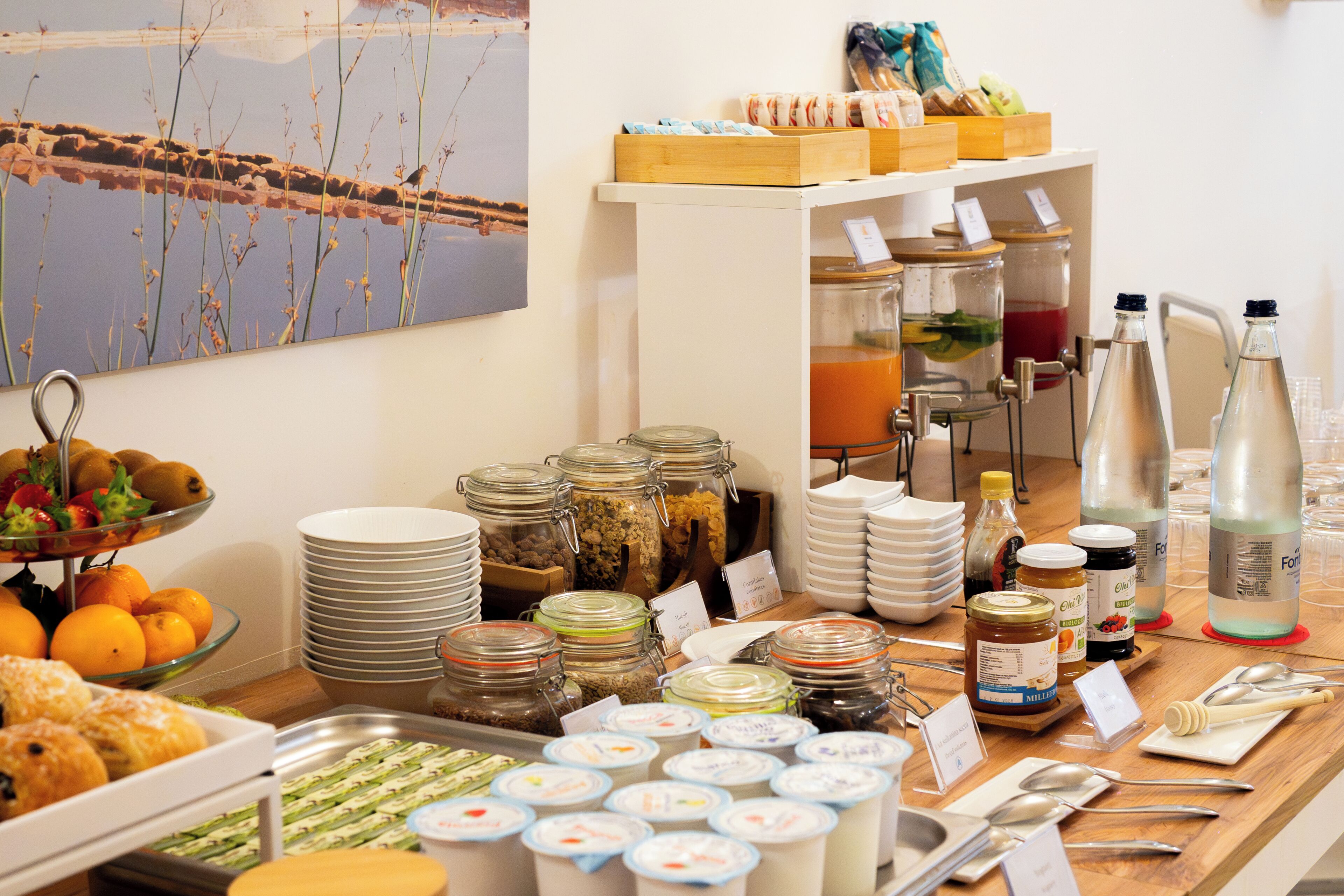 A buffet with various food items, including fruits, pastries, and condiments.