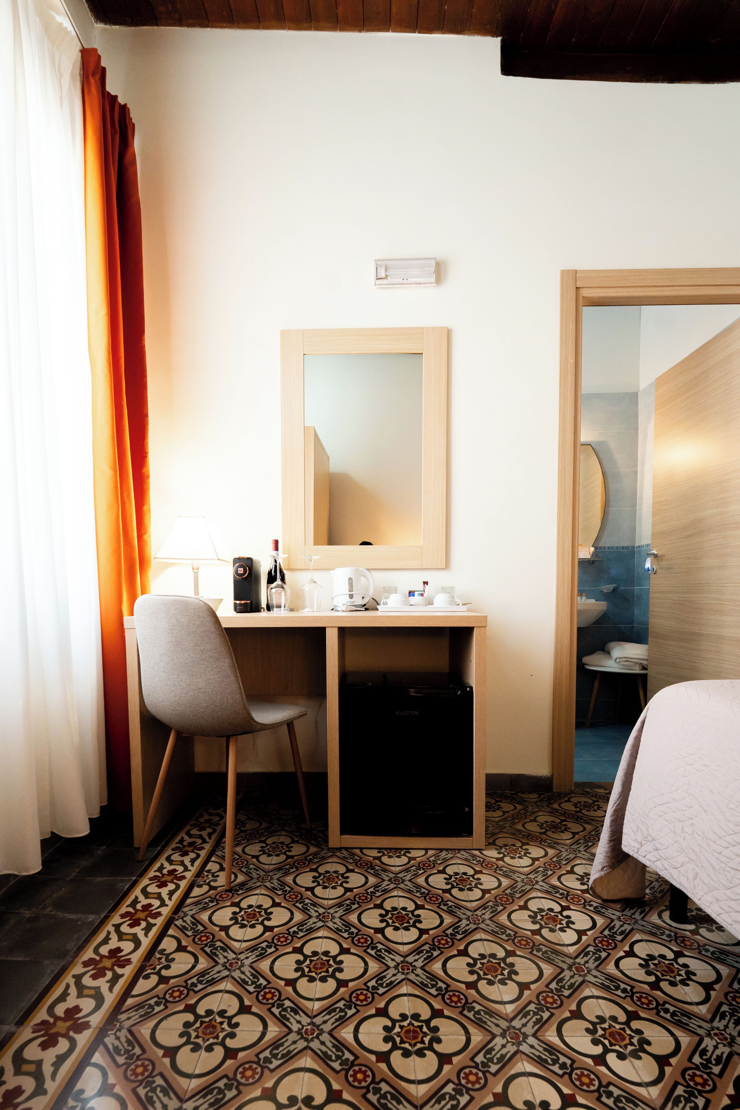 Quarto de hotel com uma escrivaninha, cadeira e cama.