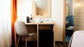 Quarto de hotel com uma escrivaninha, cadeira e cama.