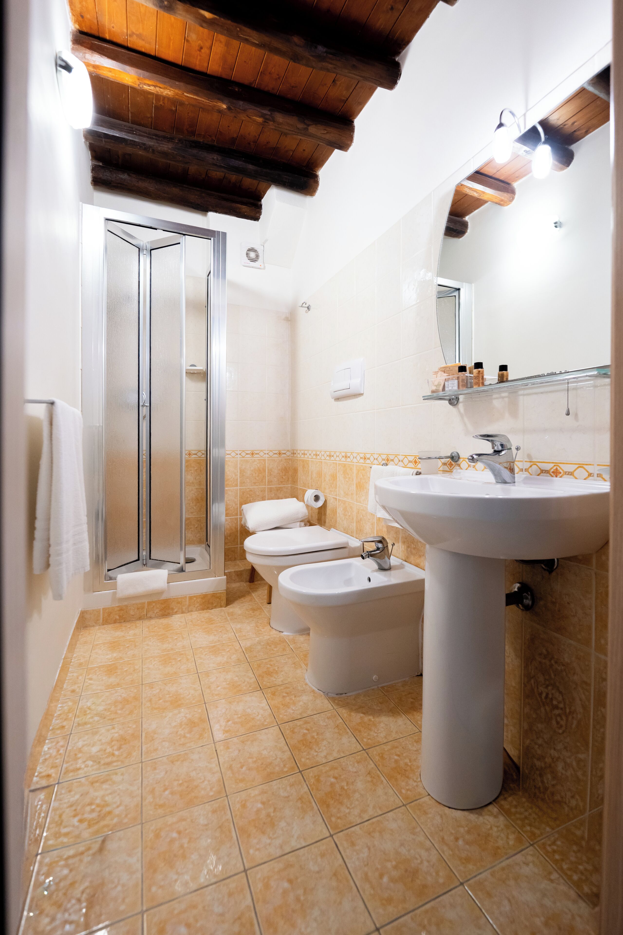 A bathroom with a shower, toilet, bidet, and sink.