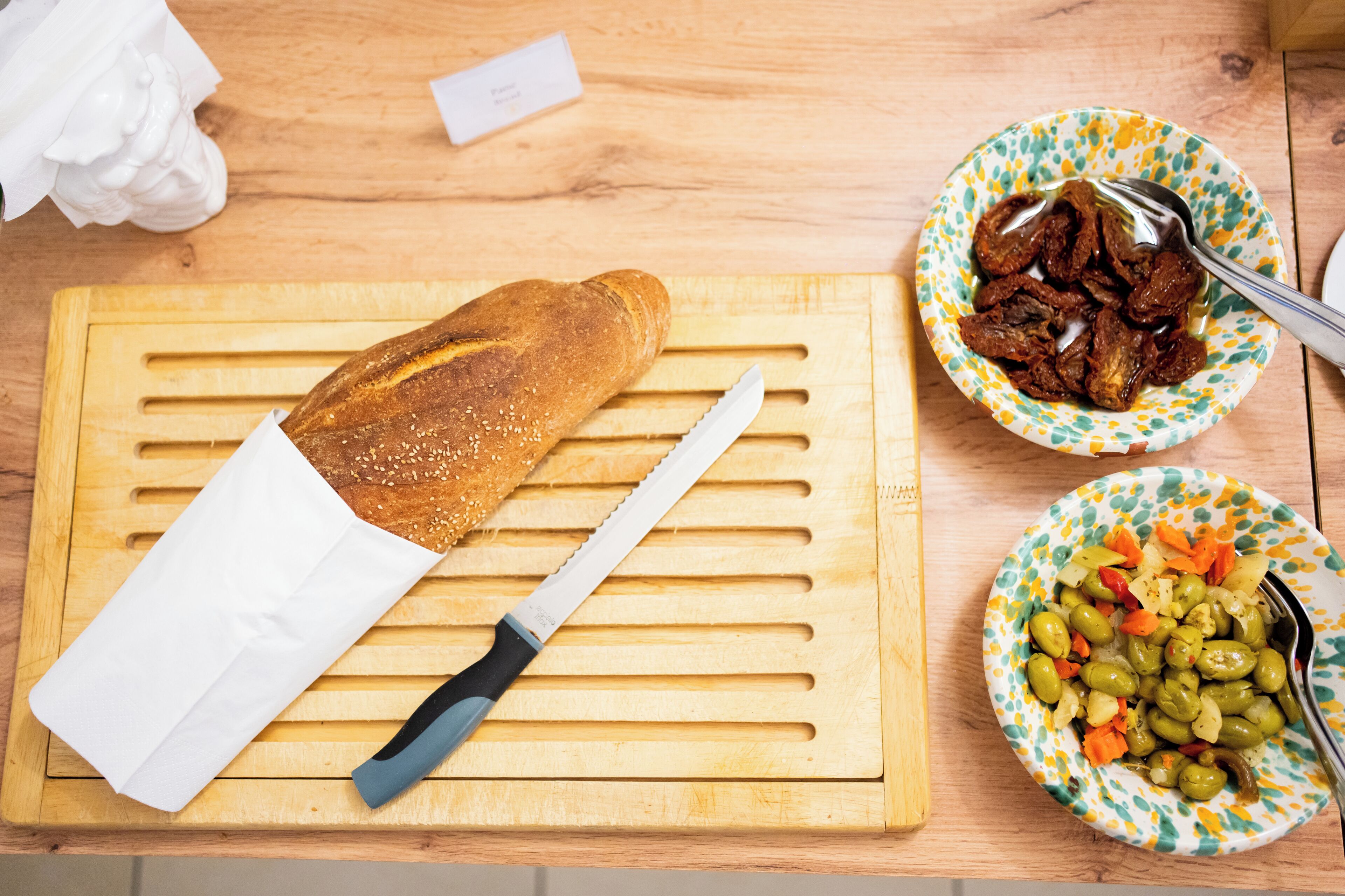 Ein Holztisch mit einem Schneidebrett, Brot, einem Messer und zwei Schüsseln mit Essen.